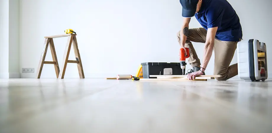 Un homme rénove le parquet de son appartement locatif