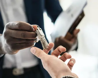 Un agent immobilier tend les clefs d'un appartment après un état des lieux d'entrée