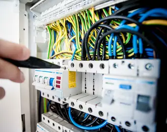 un technicien étudie le tableau électrique pour un diagnostic immobilier